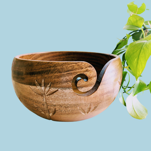 a wooden bowl sitting next to a plant
